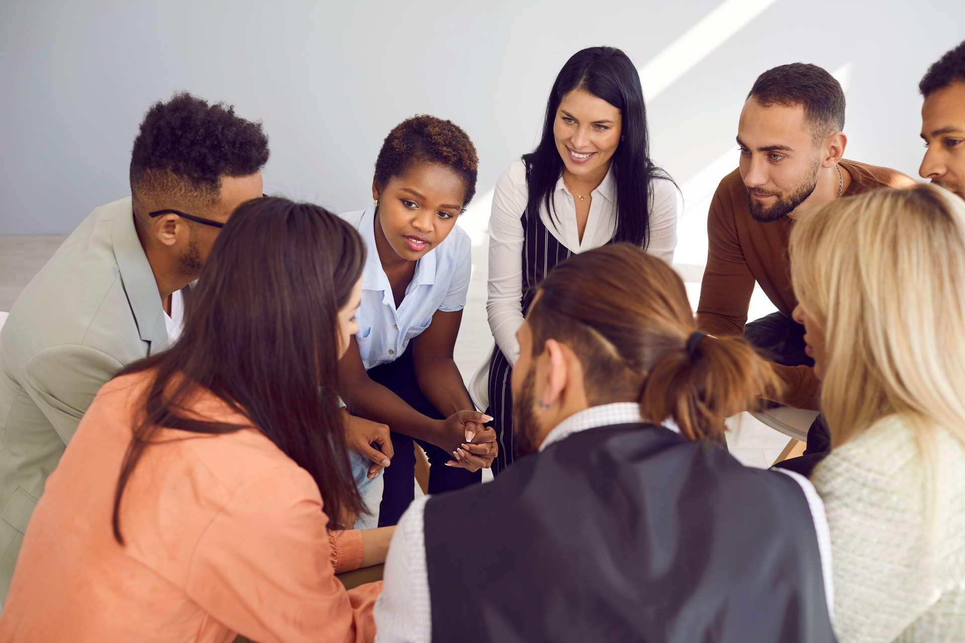 Multiracial men and women at support group meeting listen to young woman tell her story.